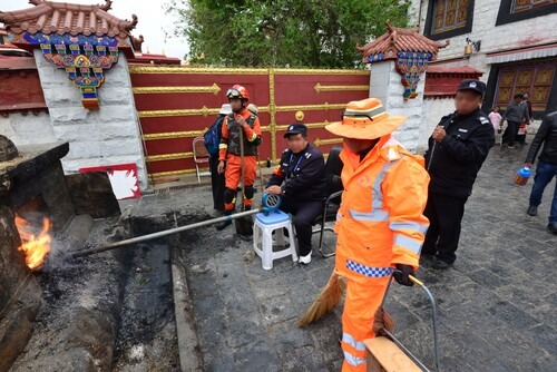 Figure 3. At the Barkor in Lhasa, a police officer operates a bellows to control the fire in a sang bum. A sanitation worker keeps the operation tidy, and a fireman stands by to put out any unexpected flames.Source: Photo by author, 2018.